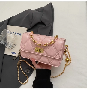 Detailed macro of pink quilted crossbody bag with gold chain and metal twist lock
