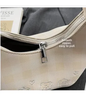Close-up of smooth silver metal zipper on a checkered crossbody bag with cute embroidery