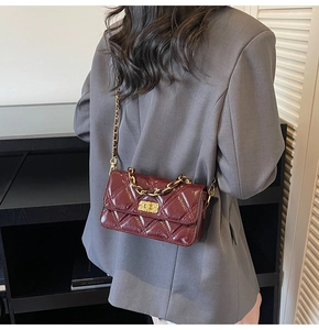 Model wearing a wine red quilted leather crossbody bag with golden chain and lock
