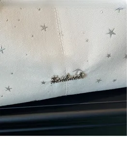 Close-up of off-white canvas texture with silver star rivets and Handmade metal logo
