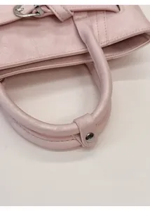 Détail du sac à main en similicuir rose avec poignées arrondies et rivets métalliques