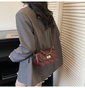 Detail shot of a wine red quilted crossbody bag with gold chain handle and twist lock
