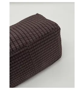 Detail of the reinforced base and stitching on a dark brown plaid canvas shoulder bag