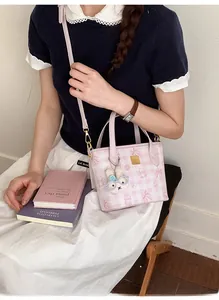 Detailed view of pink plaid crossbody bag with cute bear print and white rabbit plush charm