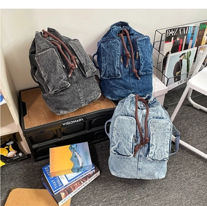 Three washed denim backpacks in grey, dark blue and light blue with drawstring closure