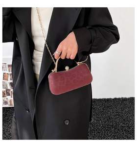 Détail d'une pochette en velours léopard bordeaux avec chaîne dorée et fermoir bijou