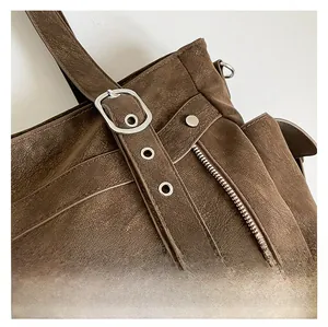Detail of dark brown tote bag showing textured leather material and silver buckle hardware