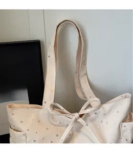 Detail of cream canvas tote bag with silver star prints and decorative bow straps