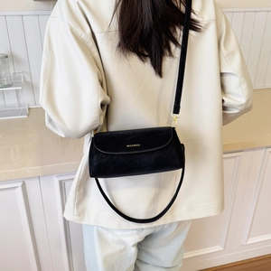 Détail d'un sac bandoulière en daim noir avec lettrage MULANKOU doré et bandoulière en cuir