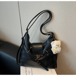 Détail d'un sac hobo en cuir noir avec bandoulière réglable et breloque ours en peluche