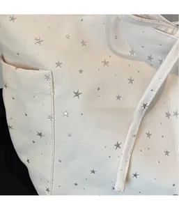 Detail of off-white canvas tote bag featuring silver star metal rivets and fine stitching