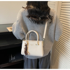 Detail of white leather crossbody tote with brown resin chain and brand logo