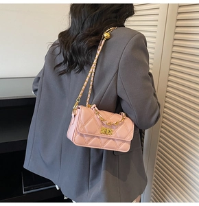 Detail of pink quilted crossbody bag with gold chain strap on a grey blazer outfit