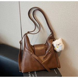 Détail du sac fourre-tout en cuir mat marron avec bandoulière et pendentif ours