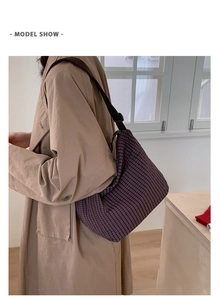 Detail of a purple plaid crossbody bag showing a half-moon shape and canvas texture