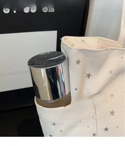 Detail view of the side storage pocket on an off-white canvas tote bag with star pattern