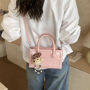 Pink patent leather crossbody bag with flower embossing and a cute teddy bear charm