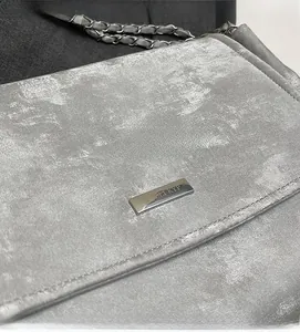 Detailed close-up of silver tote bag showing metallic texture and brand plaque