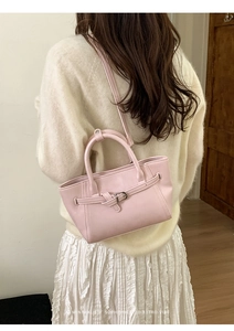Détail du sac à main rose en cuir avec boucle, porté par un mannequin en style rétro