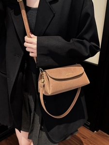 Sac bandoulière carré en daim marron porté avec un costume noir pour un look moderne chic