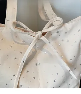 Close-up of canvas tote bag with silver star prints and a stylish tied ribbon bow detail