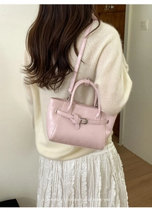 Détail du sac à main rose minimaliste avec boucle dorée et bandoulière sur le mannequin