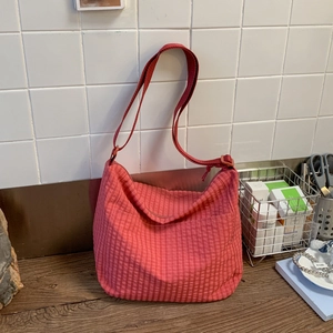 Detailed view of the red checkered pattern and adjustable strap on this crescent bag