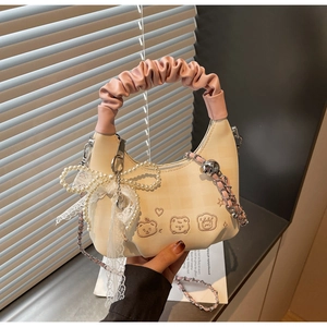 Detail of cream crossbody bag with bear embroidery, pink ruched handle and pearl bow