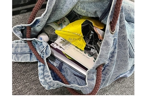 Top-down macro view of spacious denim drawstring bag interior with daily essentials and cords