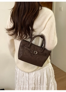 Détail du sac à main rétro en cuir marron foncé avec boucle argentée en forme de D
