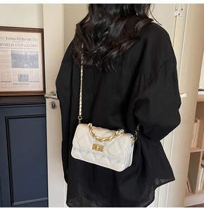 Close-up of cream quilted bag featuring gold chain strap and metal turn-lock closure