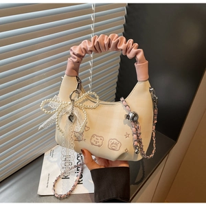 Detail of the white crossbody bag featuring bear embroidery and a large pearl bow accent