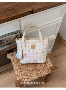 Close-up of pink checkered mini tote bag with cartoon illustrations and plush rabbit charm
