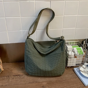 Detail of dark green checkered tote bag with adjustable nylon strap and large pocket