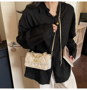 Close-up of quilted beige crossbody bag with gold chain strap and metal turn-lock