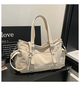 Detailed close-up of cream leather tote bag featuring silver hardware and side pocket