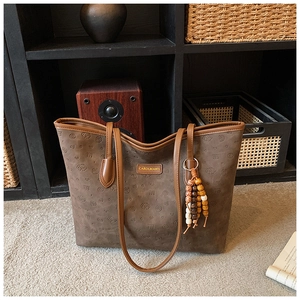 Detail of a dark brown embossed tote bag with heart patterns and wooden bead tassel