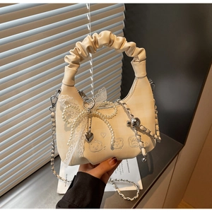 Detail of cream pleated cloud bag with lace bow and cute bear embossed leather texture