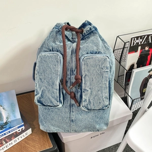 Detail of light blue denim backpack with drawstring closure and large front pockets