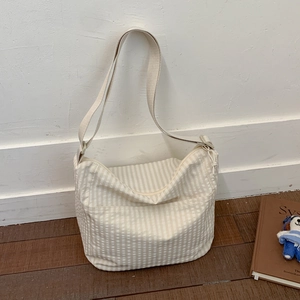 Detailed view of casual striped canvas hobo bag with adjustable strap on wooden floor