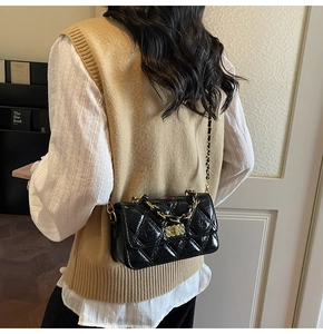 Detail of a black quilted chain shoulder bag shown from the back view on a model