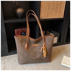 Detail of deep brown tote bag with embossed dog patterns and vintage wooden beads