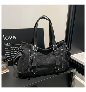 Detail view of black vintage tote bag with silver metal buckles and textured leather finish