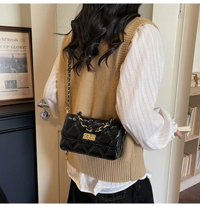 Quilted black crossbody bag with golden chain strap shown on a model in an indoor setting