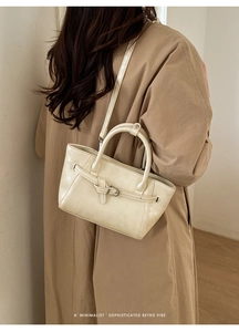 Gros plan d'un sac à main minimaliste crème en cuir avec boucles argentées et rétro