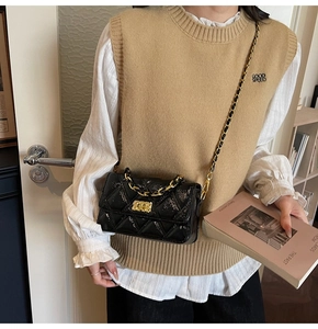 Detail of a black quilted crossbody bag with gold chain and vintage faux leather texture