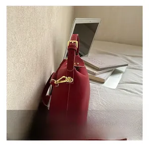 Close-up of elegant red bucket bag with refined gold hardware and adjustable strap