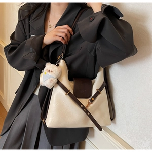 Détail d'un sac cabas blanc avec bordure marron et pendentif ours en peluche