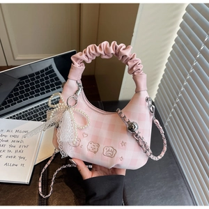 Detail of pink plaid bag with lace bow charm and pearl strap on office desk