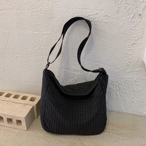 Macro detail of black checkered nylon crescent bag featuring adjustable shoulder strap